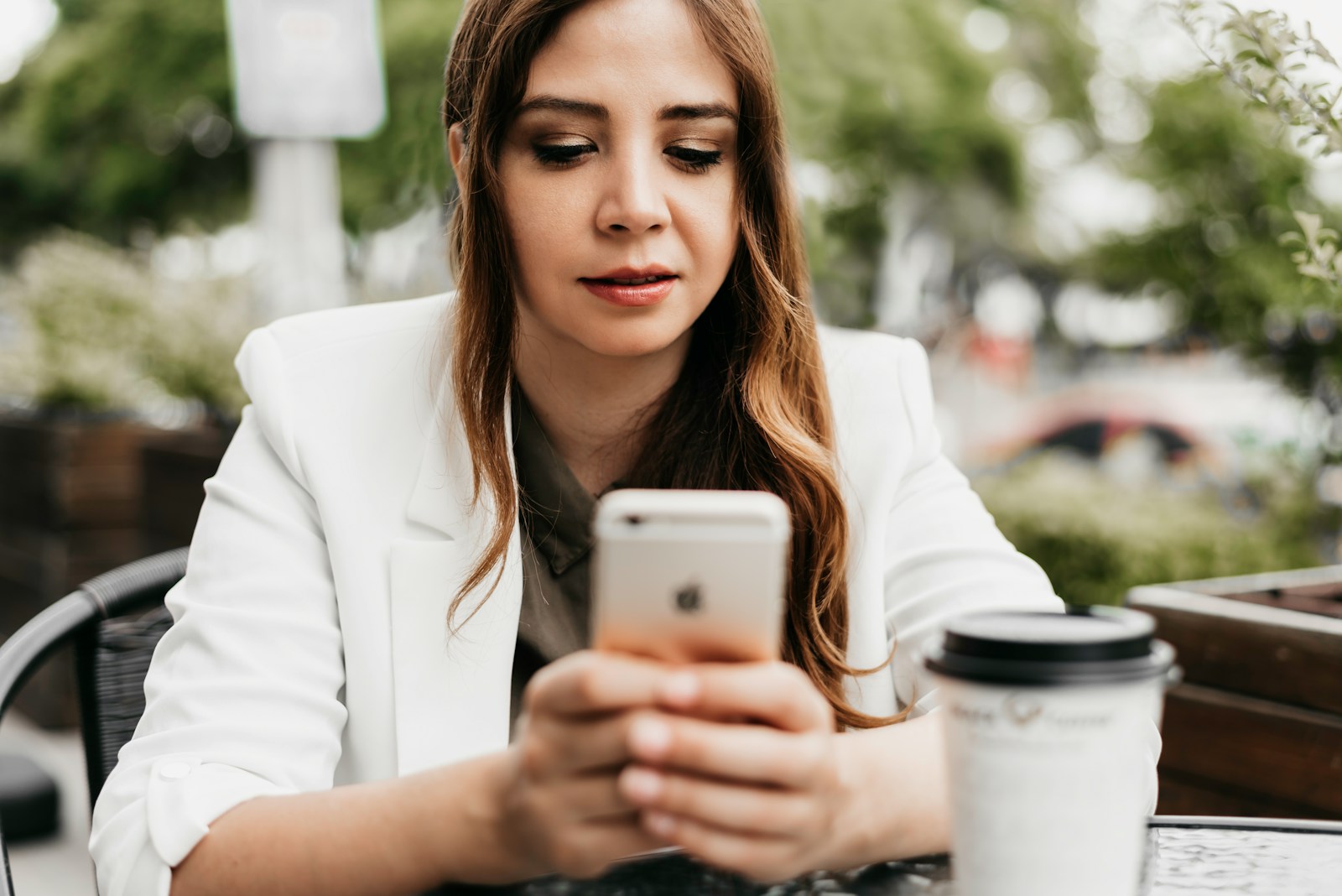 Una ragazza consulta lo smartphone seduta al tavolo di un locale